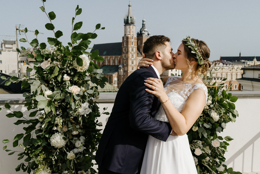 Pocałunek po ślubie na tle kościoła Mariackiego w Krakowie
